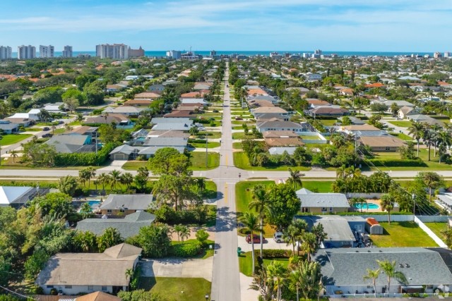 An aerial view of a neighborhood in Naples, FL, shows the Gulf of Mexico in the distance.