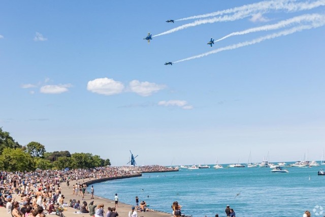 Large crowd gathered along Chicago’s lakefront watching a jet air show, showcasing vibrant waterfront living near Lake Michigan apartments. 