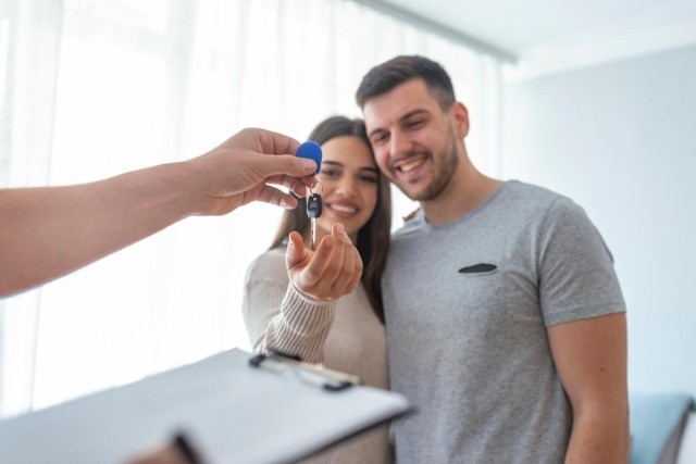 Couple receiving keys from landlord in a new apartment, addressing legal and lease-based insurance requirements.