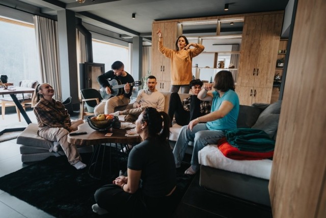 Young adults enjoying a vibrant co-living apartment with natural light, shared seating, and modern interior design — perfect for community-focused rental lifestyles.