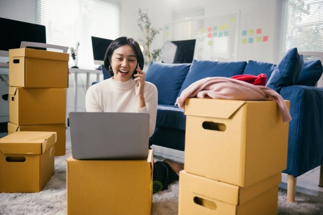 Tenant sits among moving boxes and talks on the phone.