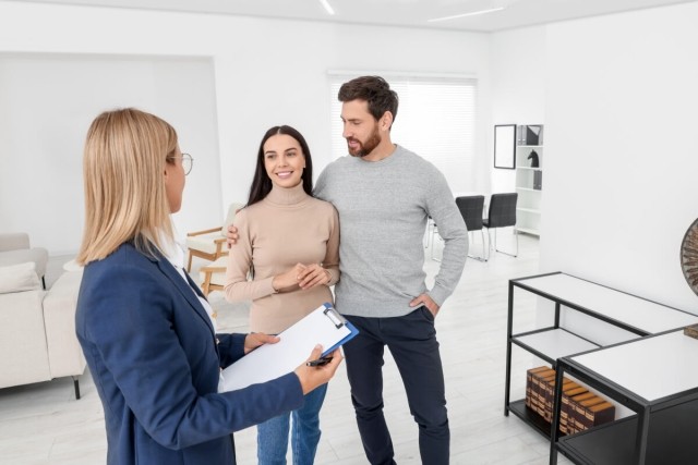 A couple touring an empty apartment with a leasing agent