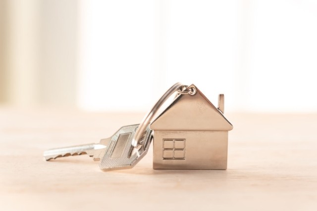 A close-up shot of a silver key attached to a house keychain.