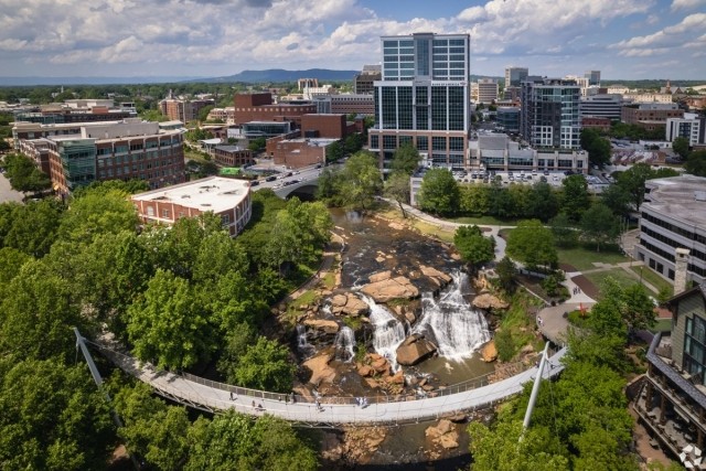 Aerial view of Falls Park and Liberty Bridge in downtown Greenville SC — perfect for apartment dwellers wanting scenic green spaces and a vibrant urban lifestyle.