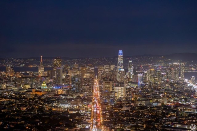 Illuminated San Francisco skyline at night featuring the Salesforce Tower, city lights, and bustling Market Street.