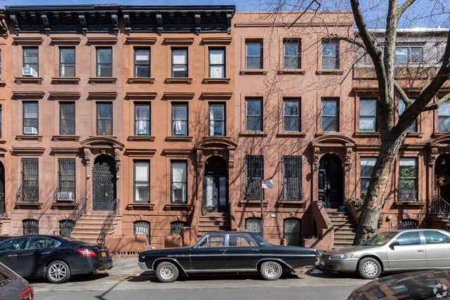 Cars parked in front of brownstone townhomes in Brooklyn, NY.