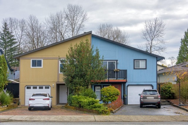 Cars parked on either side of a half-blue, half-yellow duplex.