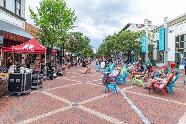 People sitting and dancing while listening to live music on a pedestrian-only street.