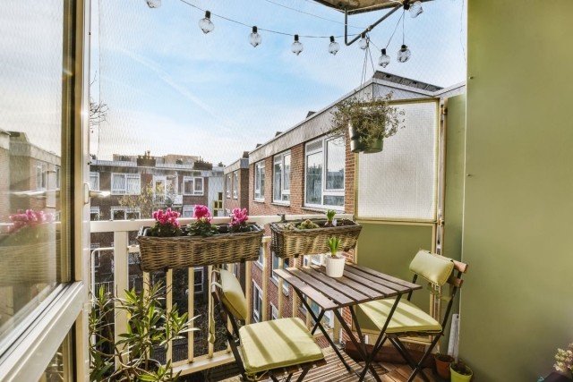A small decorated balcony space with a table and string lights