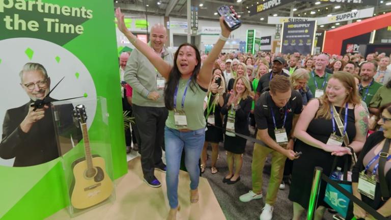 $100k winner running up to stage at NAA Apartmentalize