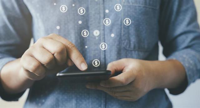 A man on his phone with icons of dollar signs coming out the phone