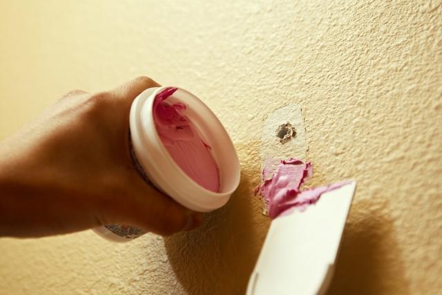 Using spackle to patch a small hole in a wall.