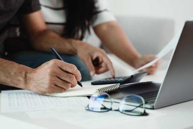 Two people sit on a couch and manage their finances.