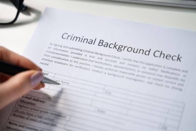 A manicured hand starts to fill out an empty background check form.
