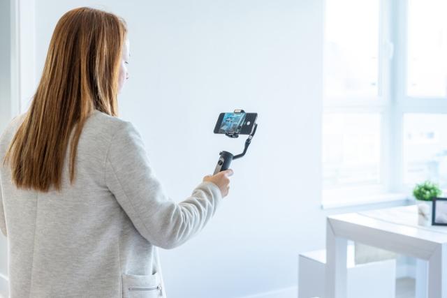 Woman recording apartment with phone.