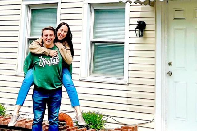 Ali and Josh Lupo (@theficouple on Instagram, Facebook, and TikTok) pose in front of property.