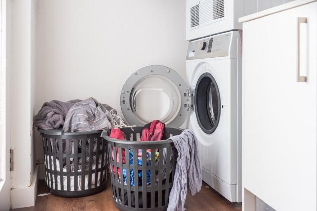 Two overflowing laundry baskets by a washing machine in an apartment.
