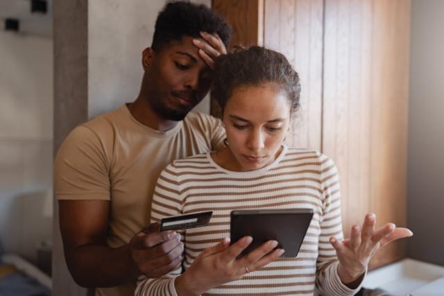 A stressed couple looks at a compromised credit card.