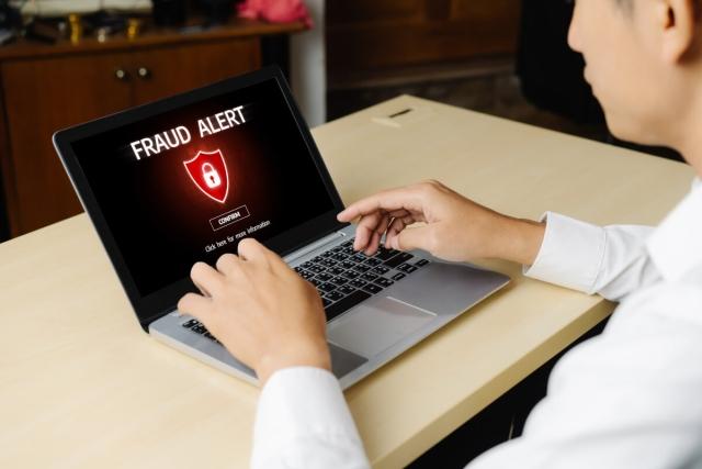 A person looks at a fraud alert on their laptop.
