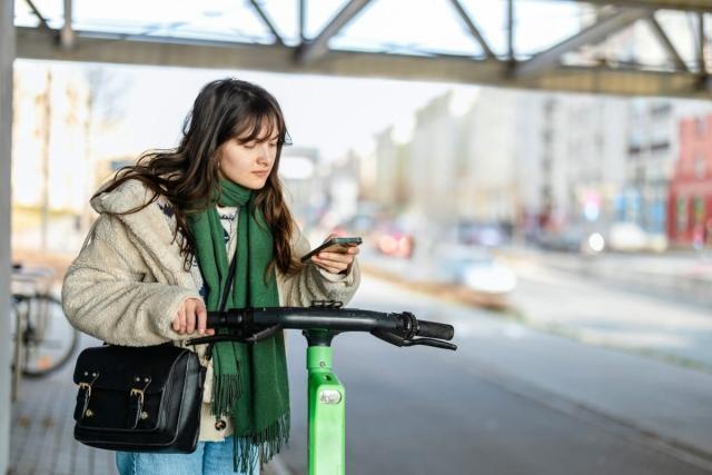 Gen Z girl navigates a city by electric scooter.