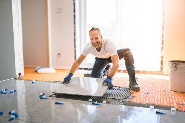 Man placing tiles on flooring.
