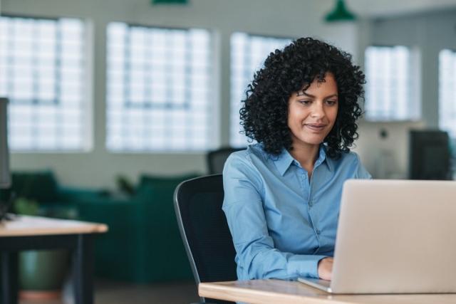 Lady sitting at a desk typing on her laptop