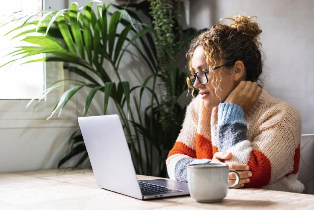 A woman looks at something on a laptop.