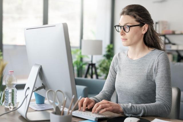 Woman typing on computer as she replies to rental inquiries.