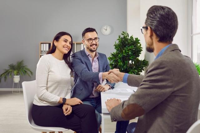 A landlord shaking hands with a couple of interested renters