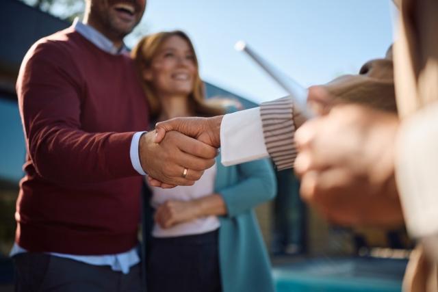 Couple shaking hands with a landlord outside the rental