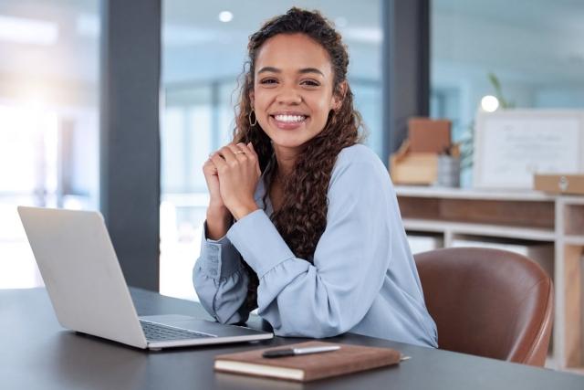 A landlord sitting a a desk with an open laptop smiling