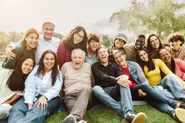 A group of people of all ages sitting outside and smiling.