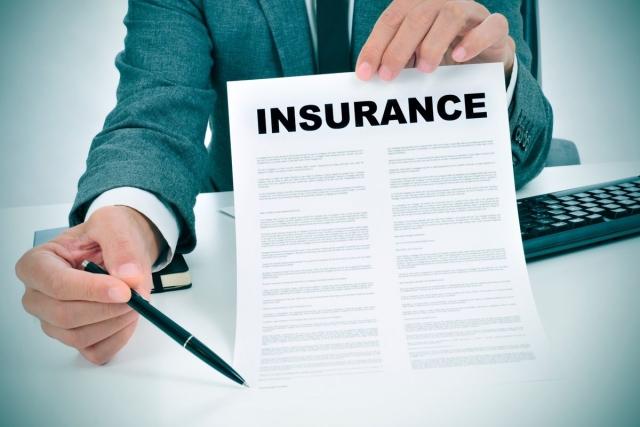 A person holding up an insurance policy document for signature.
