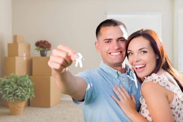 Military couple with broad smiles holding the keys to their new apartment.