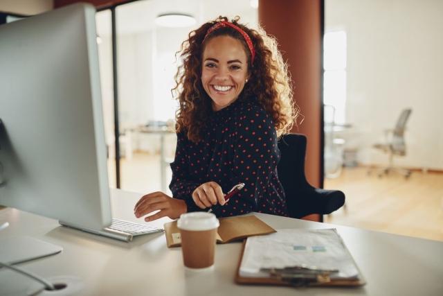 Lady sitting at desk using a computer and smiling