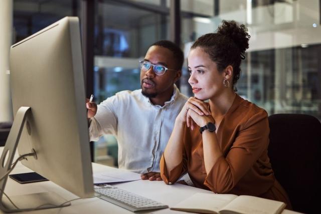 Two people in front of computer screen looking at information
