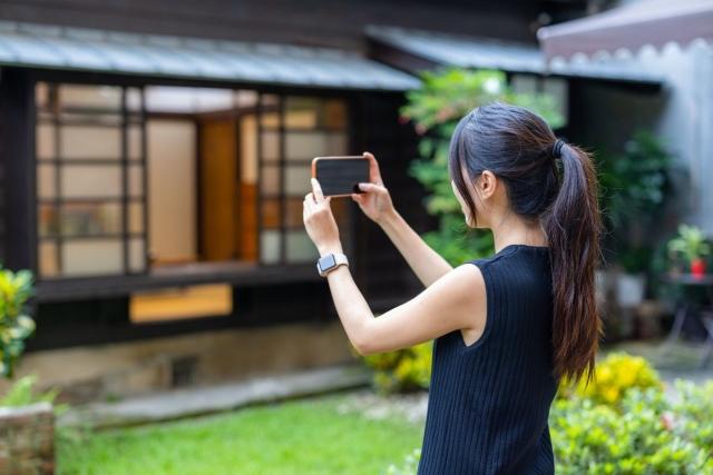 A lady taking a picture of the front of a home