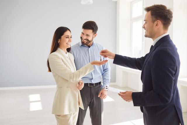A leasing agent handing the keys over to a couple