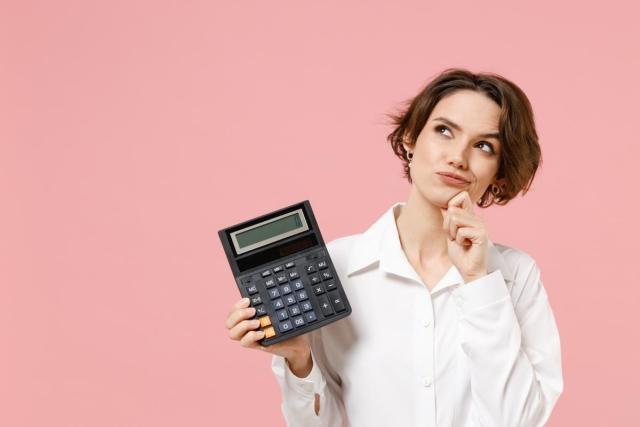 A lady is holding a calculator with an inquisitive look on her face