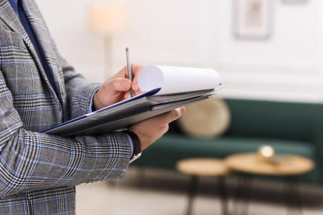 A business person holding a clipboard and a pen in an apartment