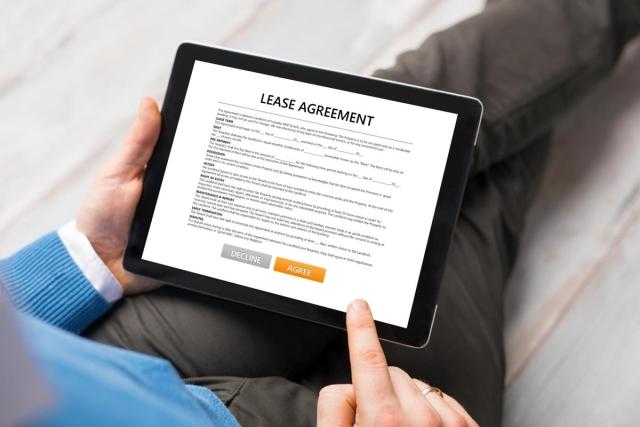 An iPad being held showing a lease agreement on the screen
