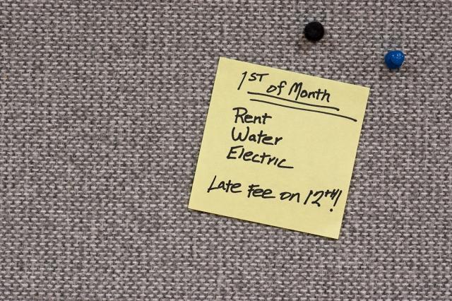 A yellow sticky note reads that rent, water, and electric bills are due the 1st of the month, and late fees are assessed on the 12th.