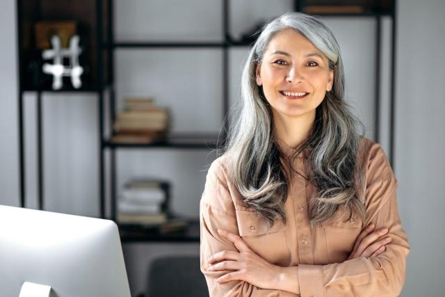 A businesswoman with a smile standing in front of her computer.