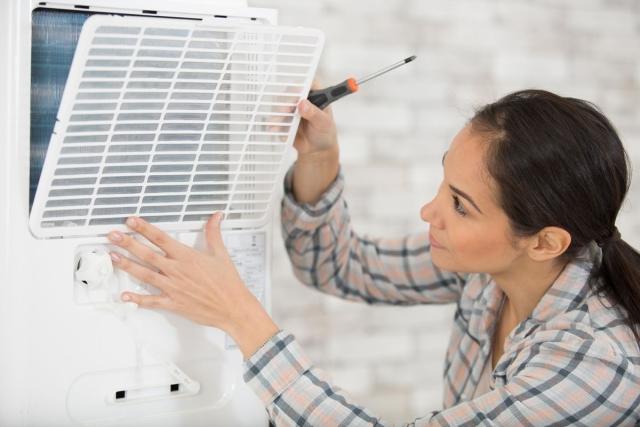 A woman replacing an air conditioning filter.