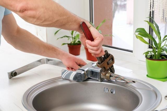 A person using tools to change a sink faucet.