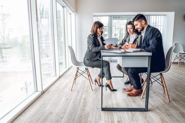 Property manager and two potential renters seated reviewing documents