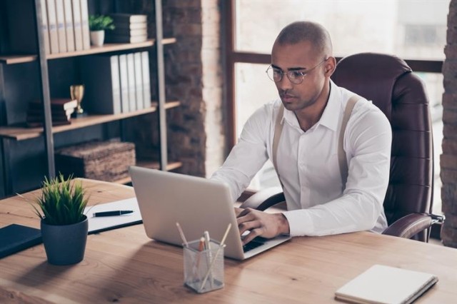 person sitting at a desk in a cozy office typing on their laptop
