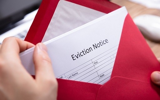 a partially opened red envelop revealing a printed eviction notice inside