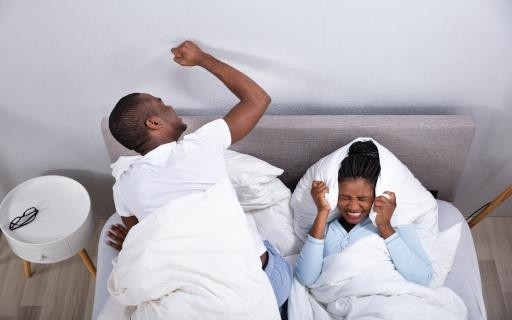 Man in bed banging fist on the wall.