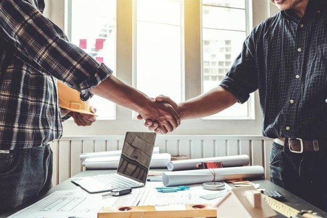 A contractor and a property manager shaking hands.